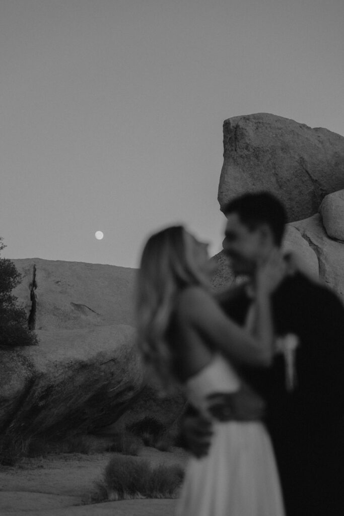 Black and white image of a couple during their elopement standing in front of boulders 