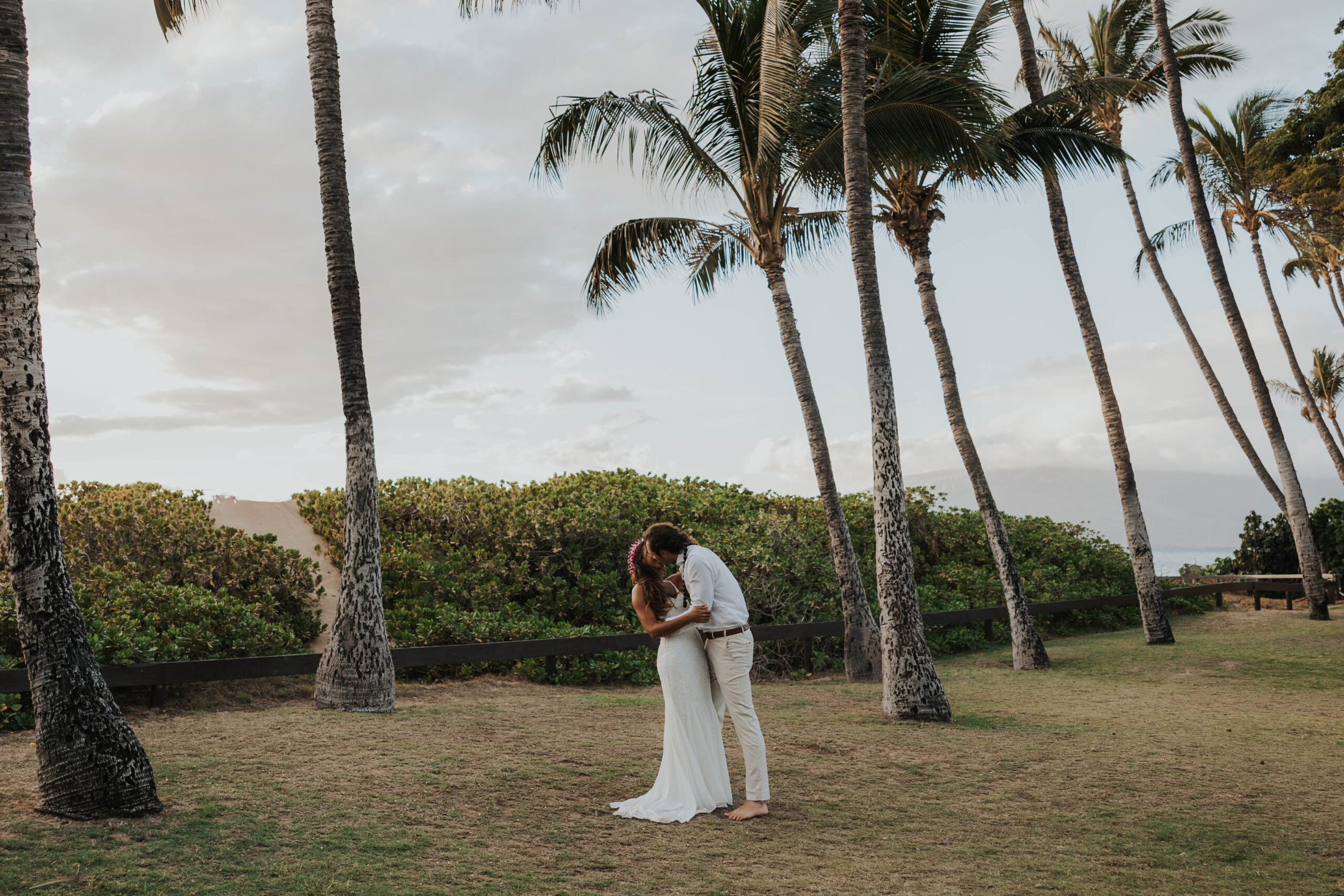 A couple eloping in Maui, Hawaii with views of palm trees and a beach 