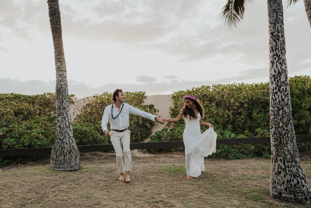 A couple eloping in Maui, Hawaii with views of palm trees and a beach 