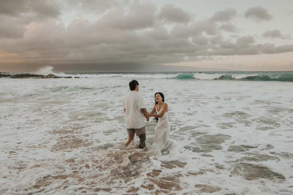 couple playing in the ocean for photoshoot