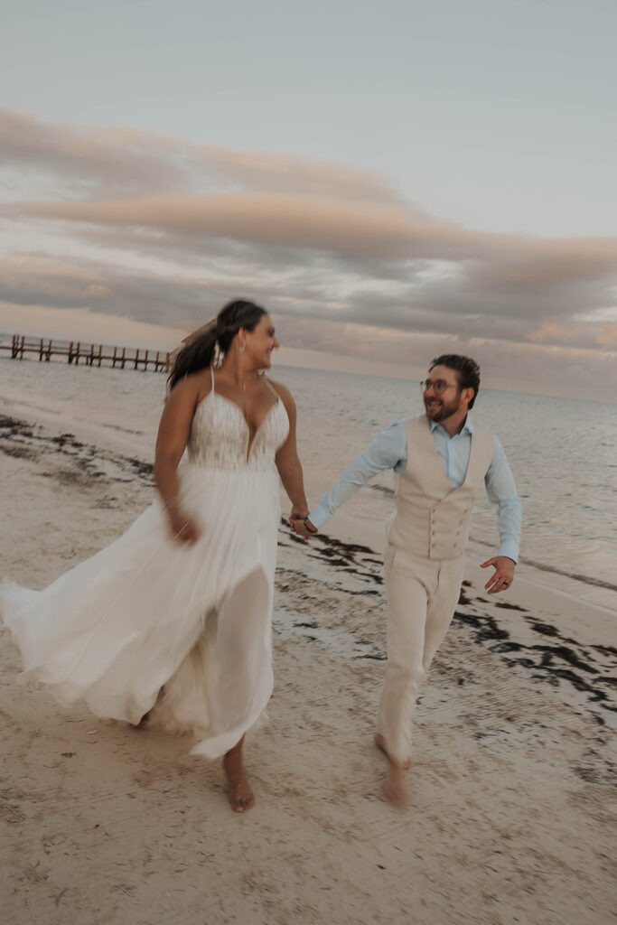 bride and groom running on the beach