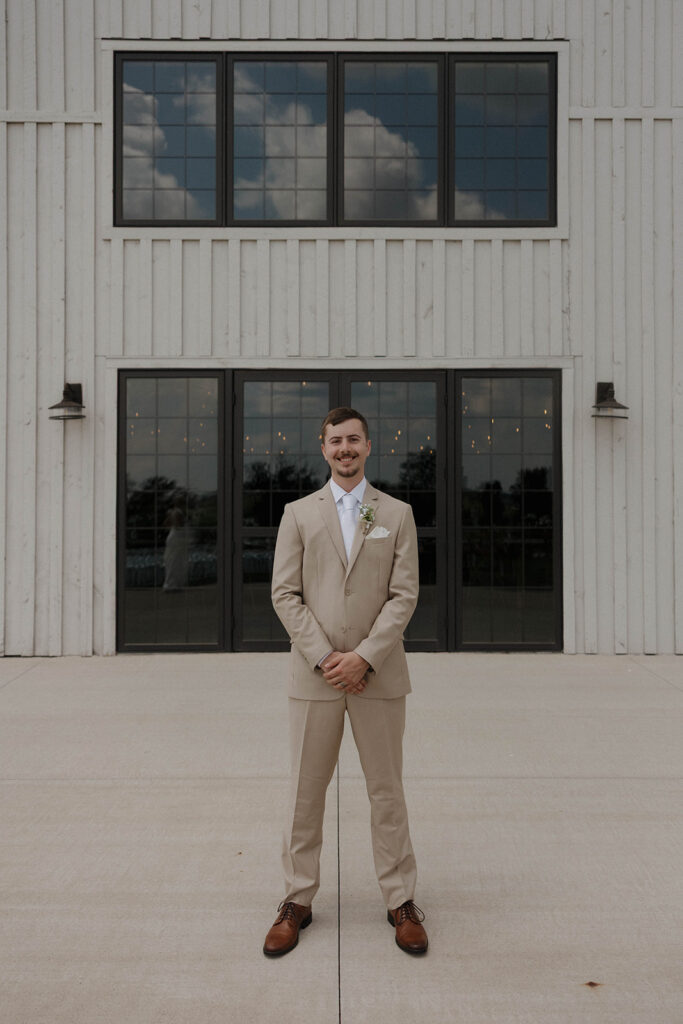 groom wedding photos in front of barn