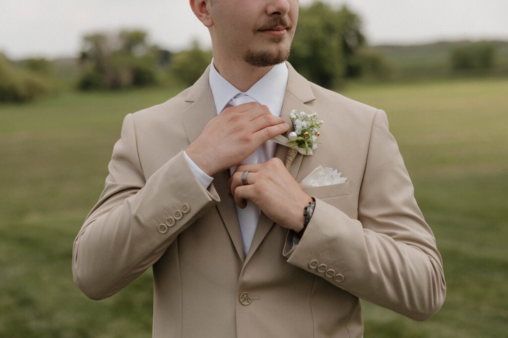 groom adjusting tie for wedding photos
