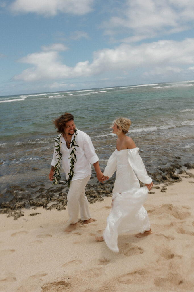 bride and groom holding hands and running on the beach