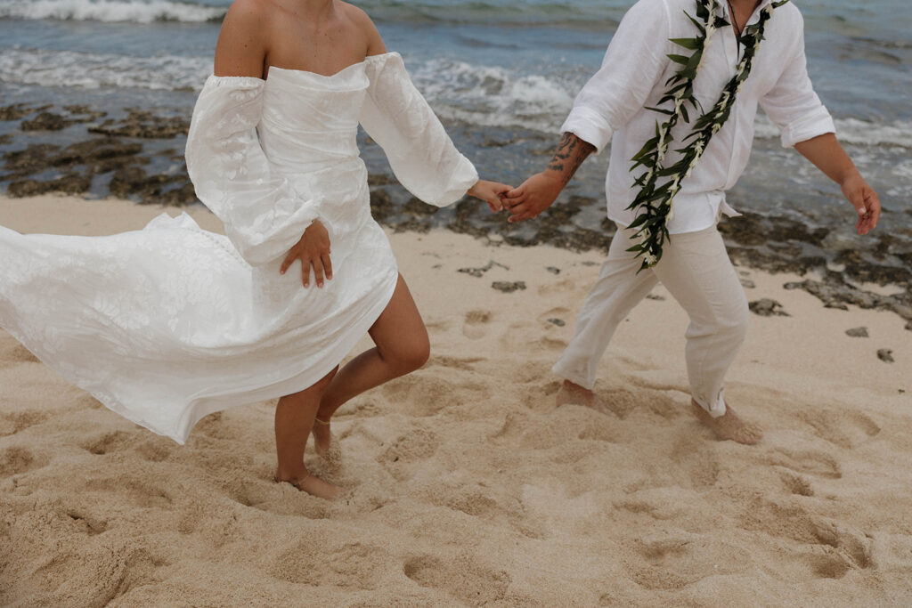 bride and groom holding hands and running on the beach