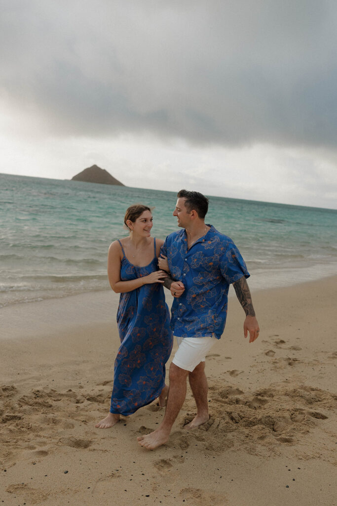 couple holding hands and walking on the beach in oahu