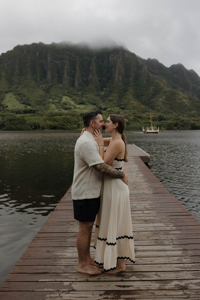 couple standing in front of the mountains on a dock in hawaii