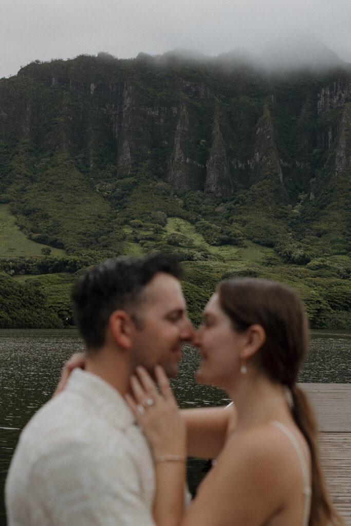 couple standing in front of the mountains on a dock in hawaii