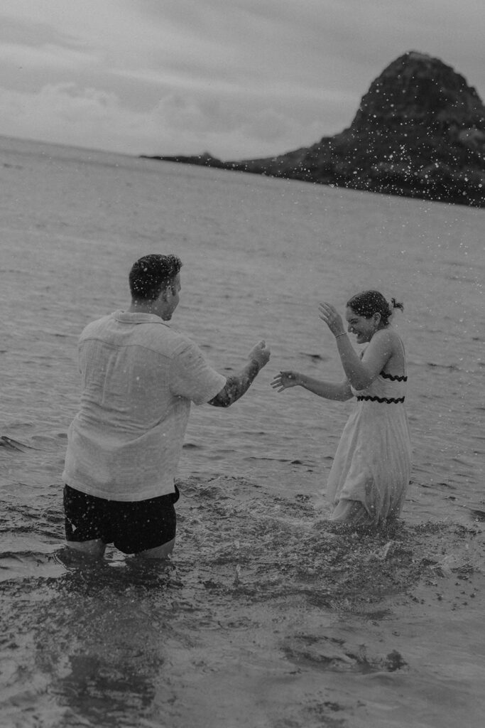 playful candid couples photo playing in the ocean and splashing water