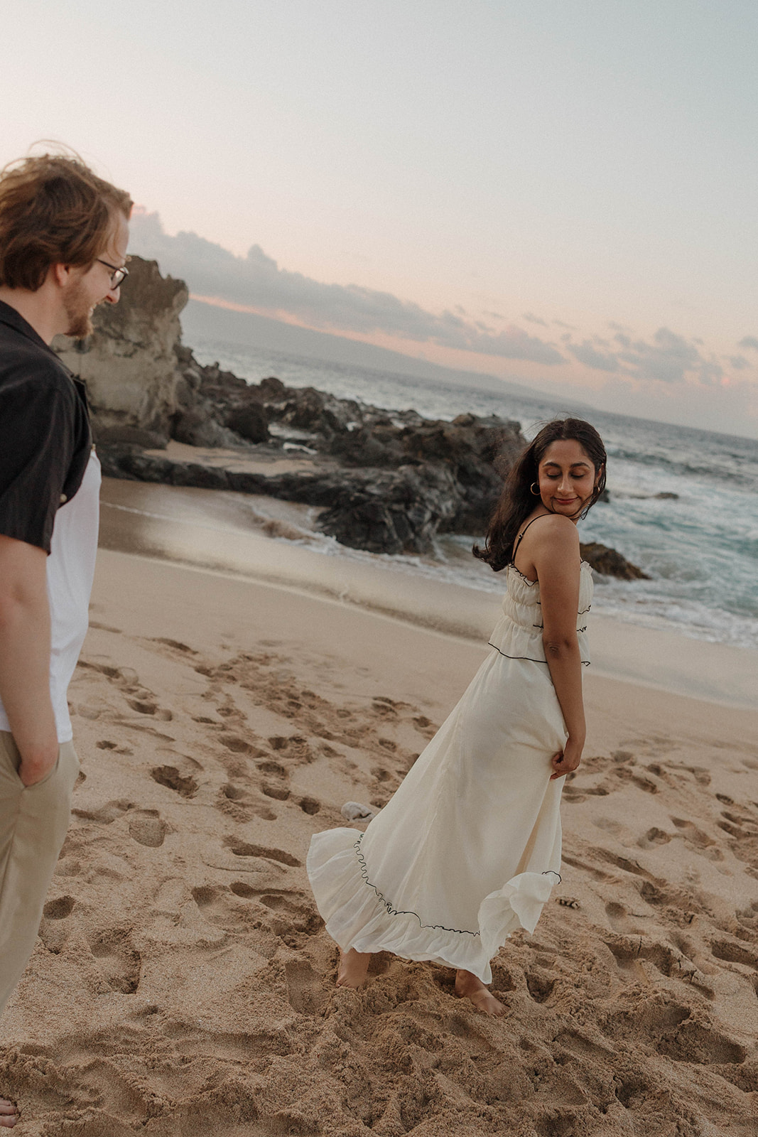 a woman standing in front of a man as he smiles at her at one of Maui's best engagement photo locations
