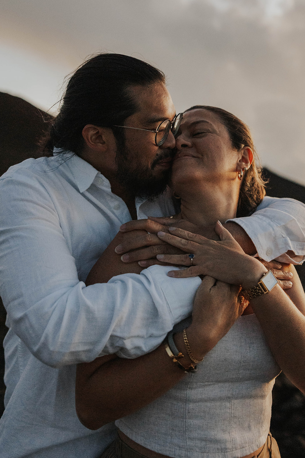 a couple snuggling into each other after their engagement 
