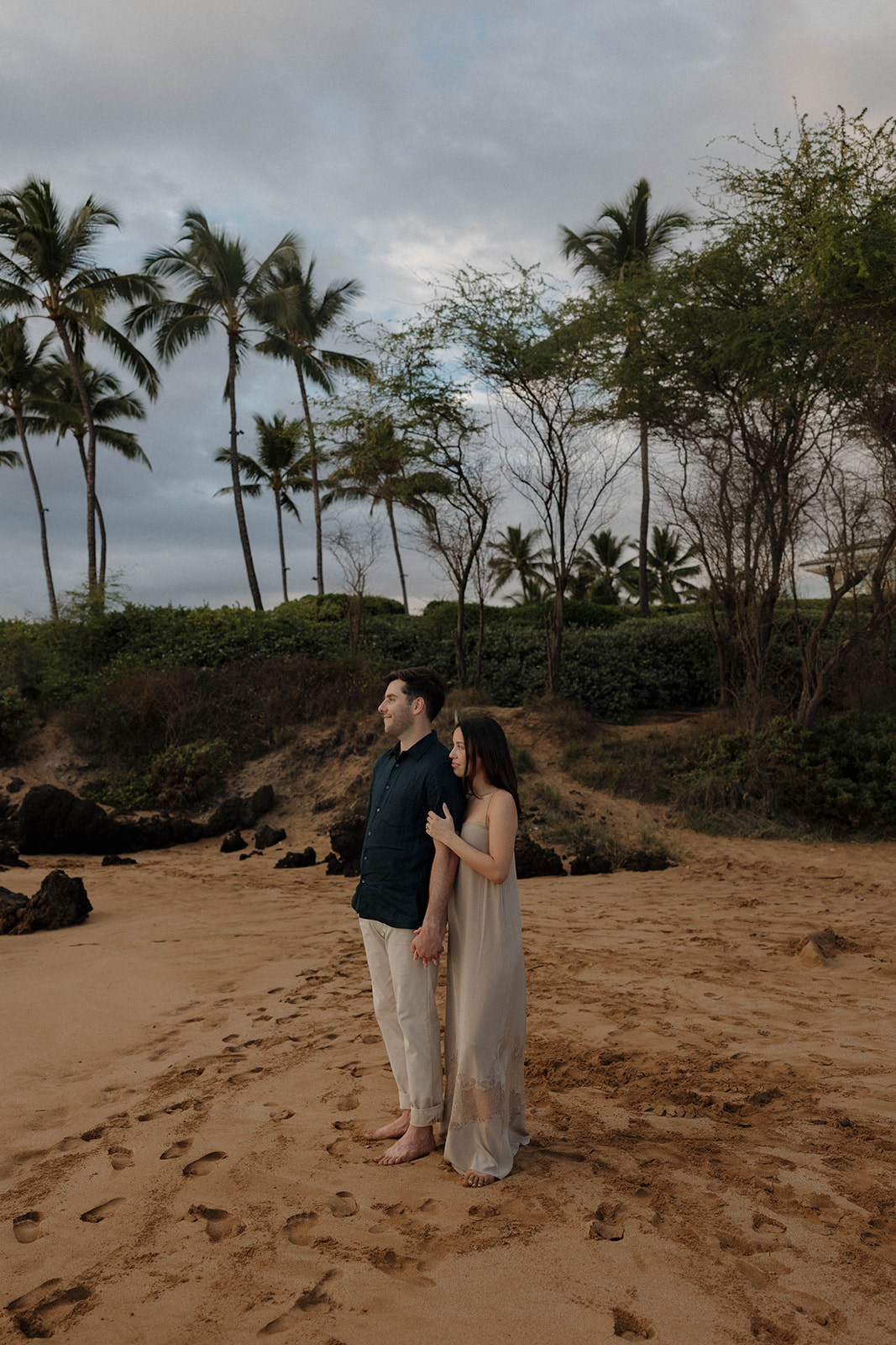 a woman standing behind a man as they look out into the ocean at one of Maui's best engagement photo locations
