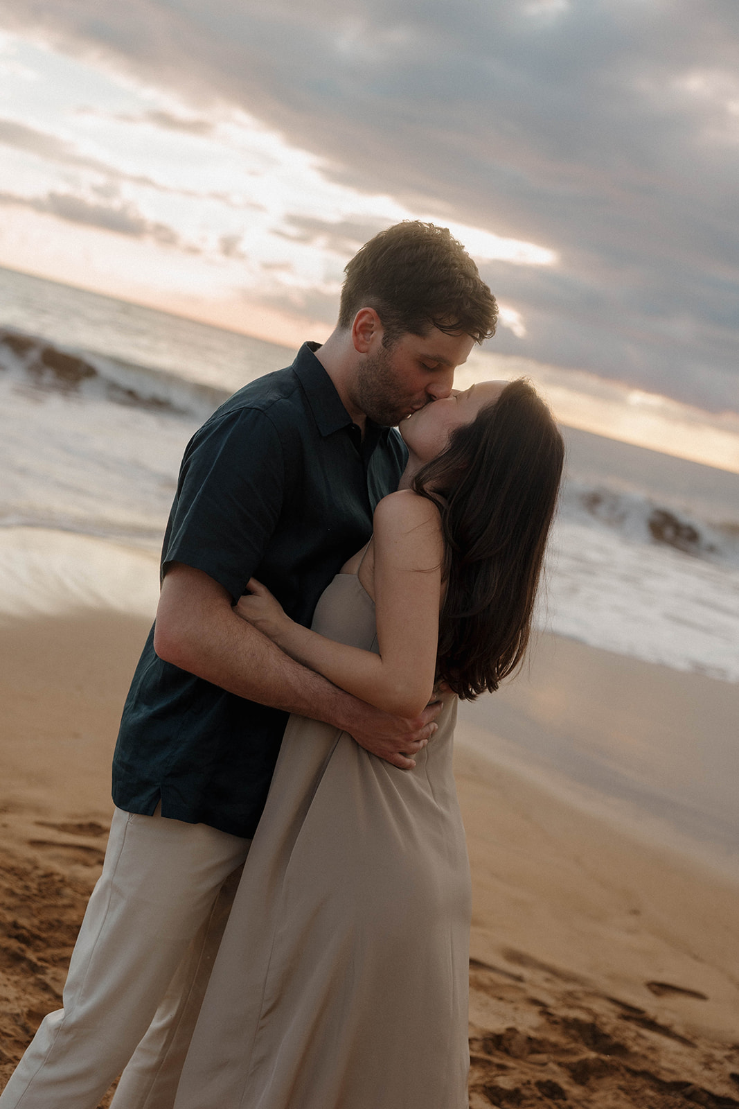 a couple kissing with the ocean behind them, captured by a Maui proposal photographer