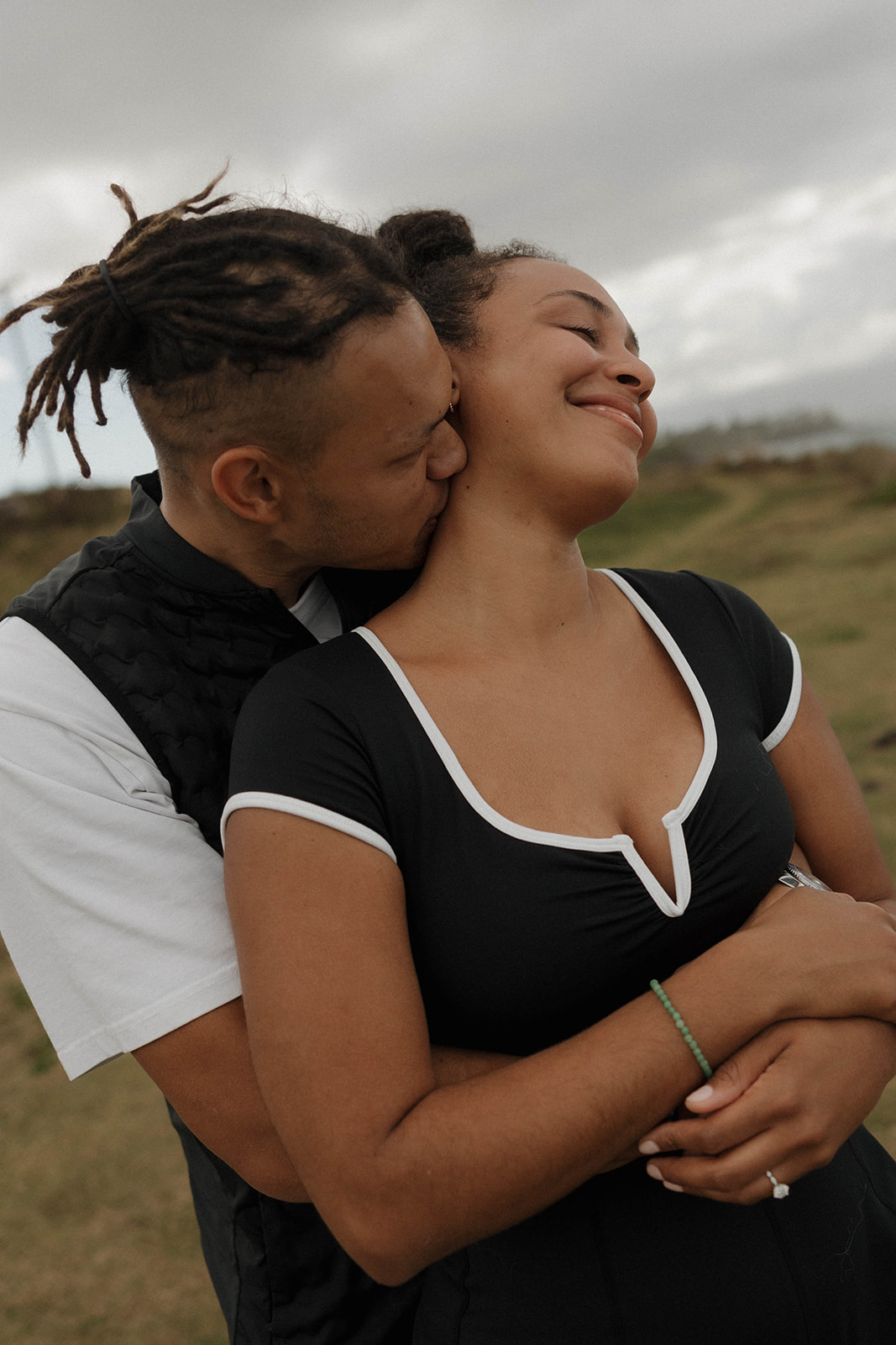 a man kissing a woman's neck after their engagement in Maui