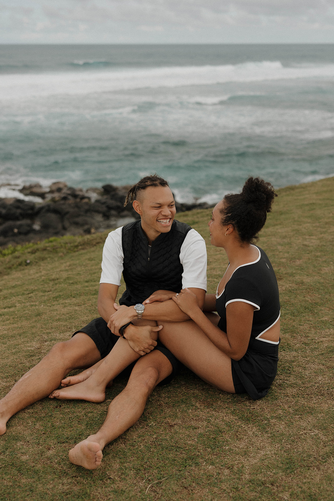 a couple sitting in the grass by the sea at one of Maui's best engagement photo locations
