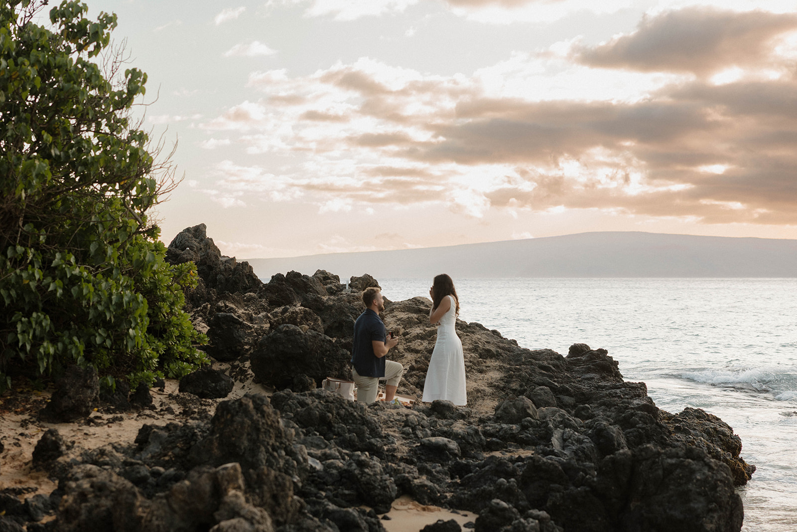 a man down on one knee proposing on a beautiful Maui beach