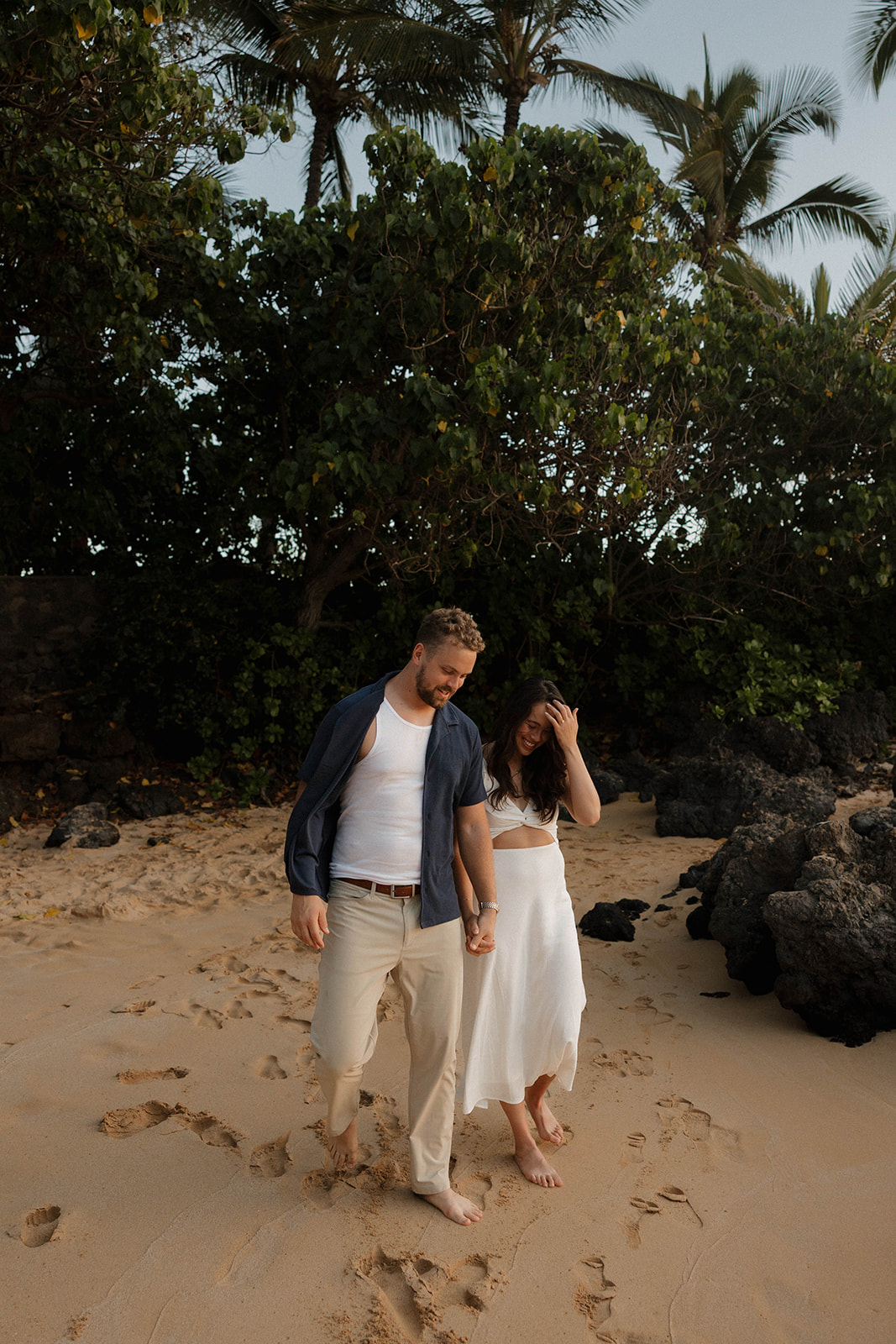 a couple walking through the beach sand together at one of Maui's best engagement photo locations

