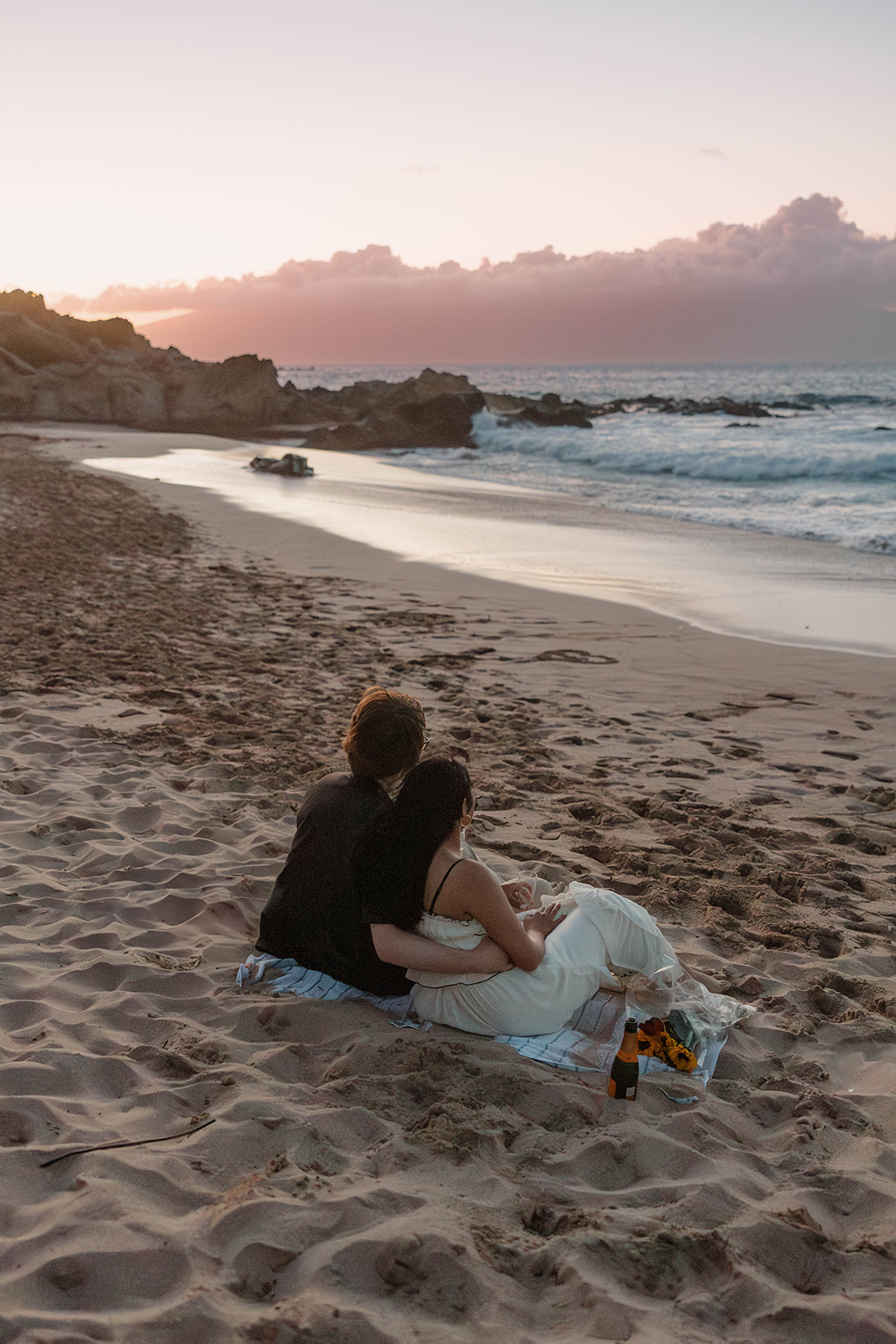 a couple sitting and watching the ocean after they just got engaged at one of Maui's best engagement photo locations
