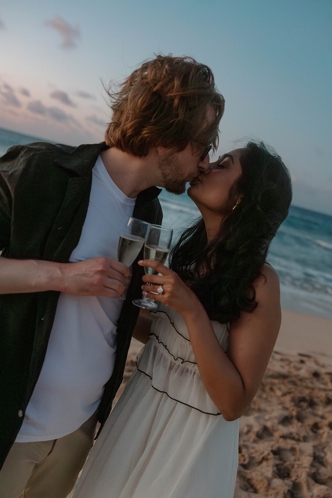 a couple kissing and having champagne during blue hour in Maui 