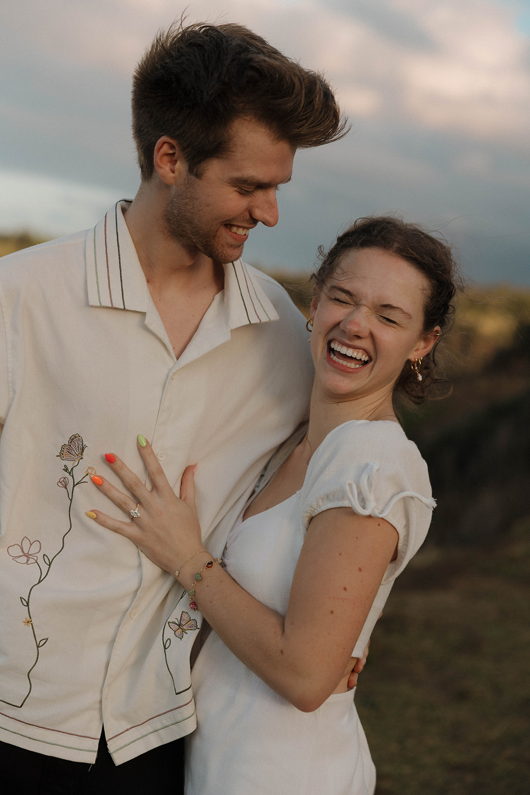 a couple in neutral engagement photo outfits, laughing in Hawaii 