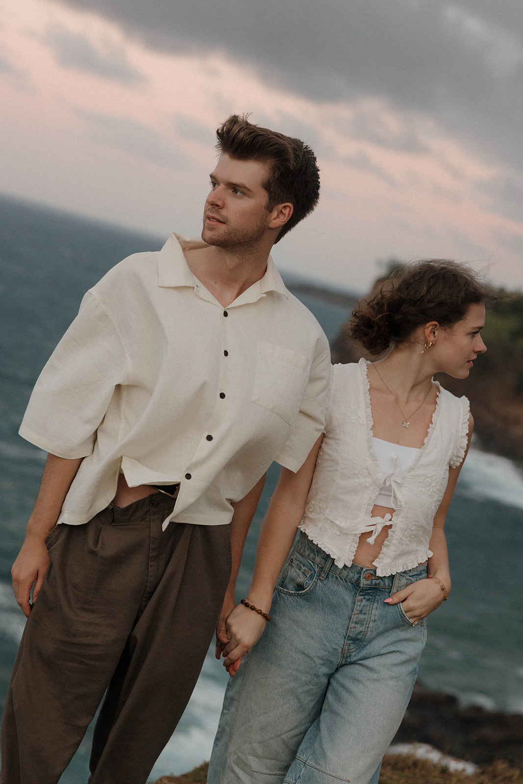 a couple holding hands and looking in opposite directions as they feature what to wear for engagement photos in Hawaii 