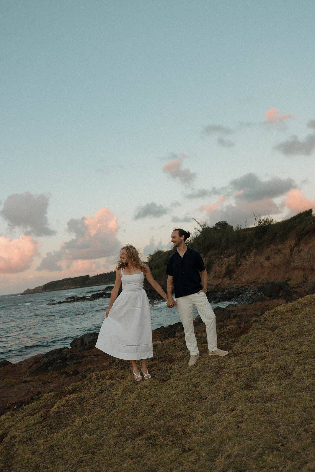 a couple standing together by the ocean for engagement photos 