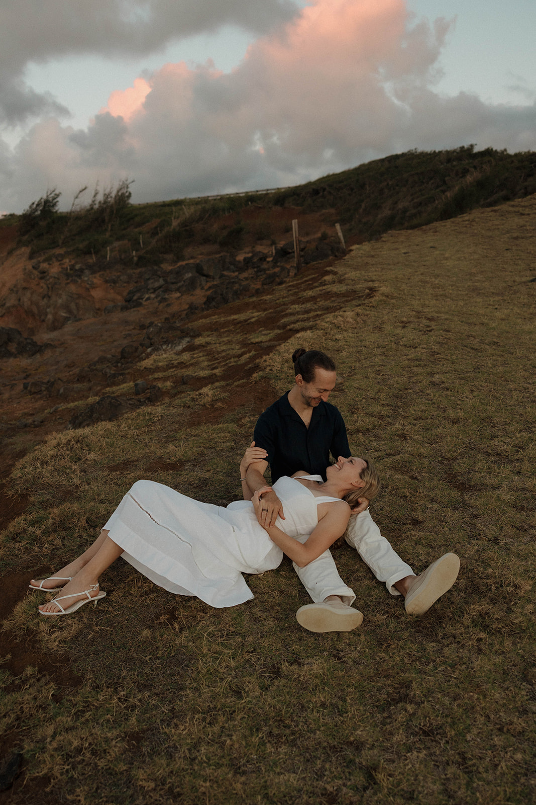a woman laying down and putting her head in a man's lap during their engagement photos 