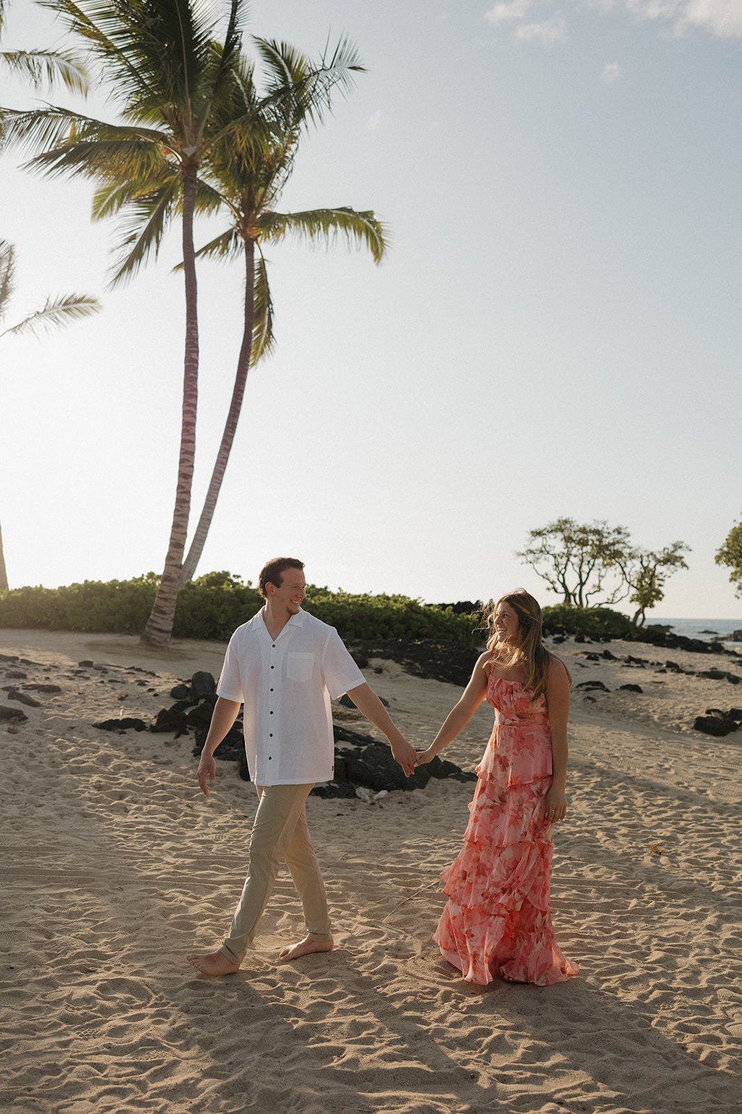 a couple on the beach holding hands showing ideas on what to wear for engagement photo outfits