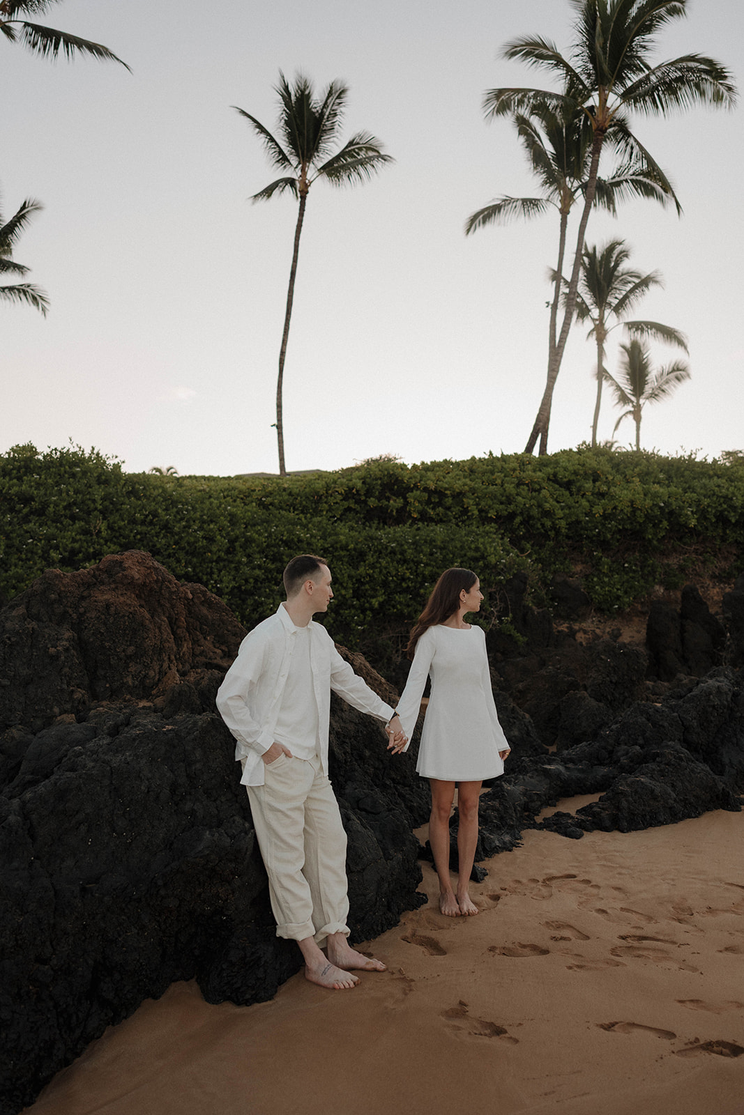 a couple in coordinating outfits on the beach for Hawaii engagement photos
