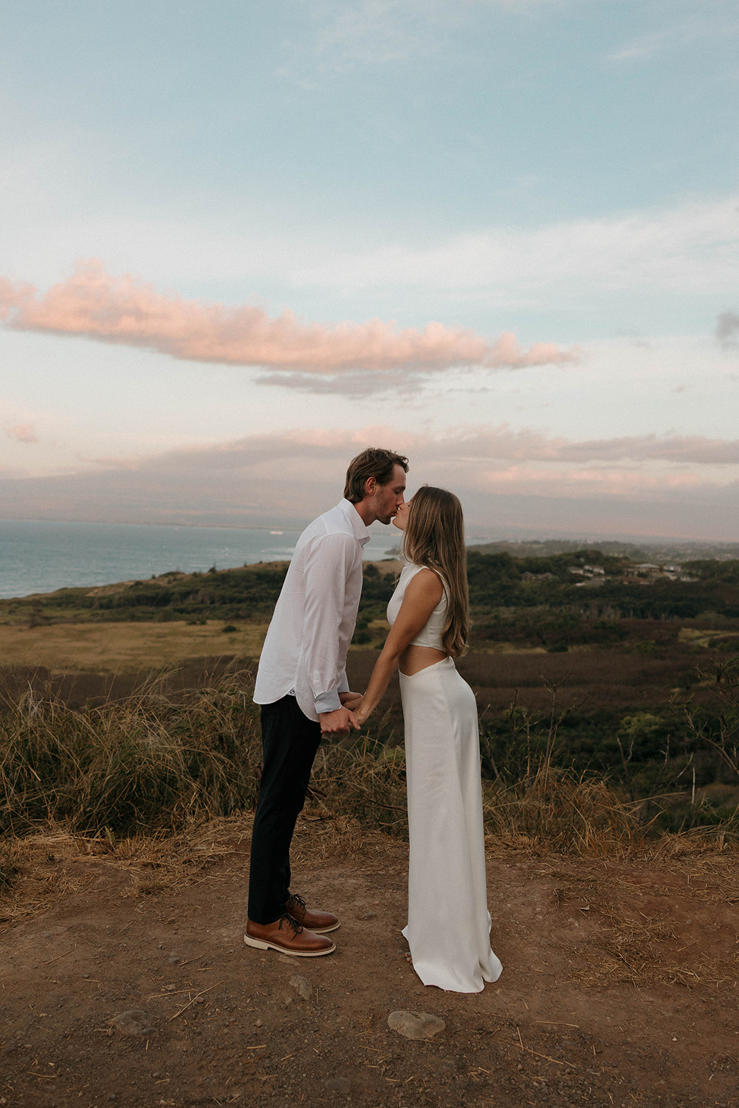 a couple kissing with a view of Hawaii's landscape behind them 