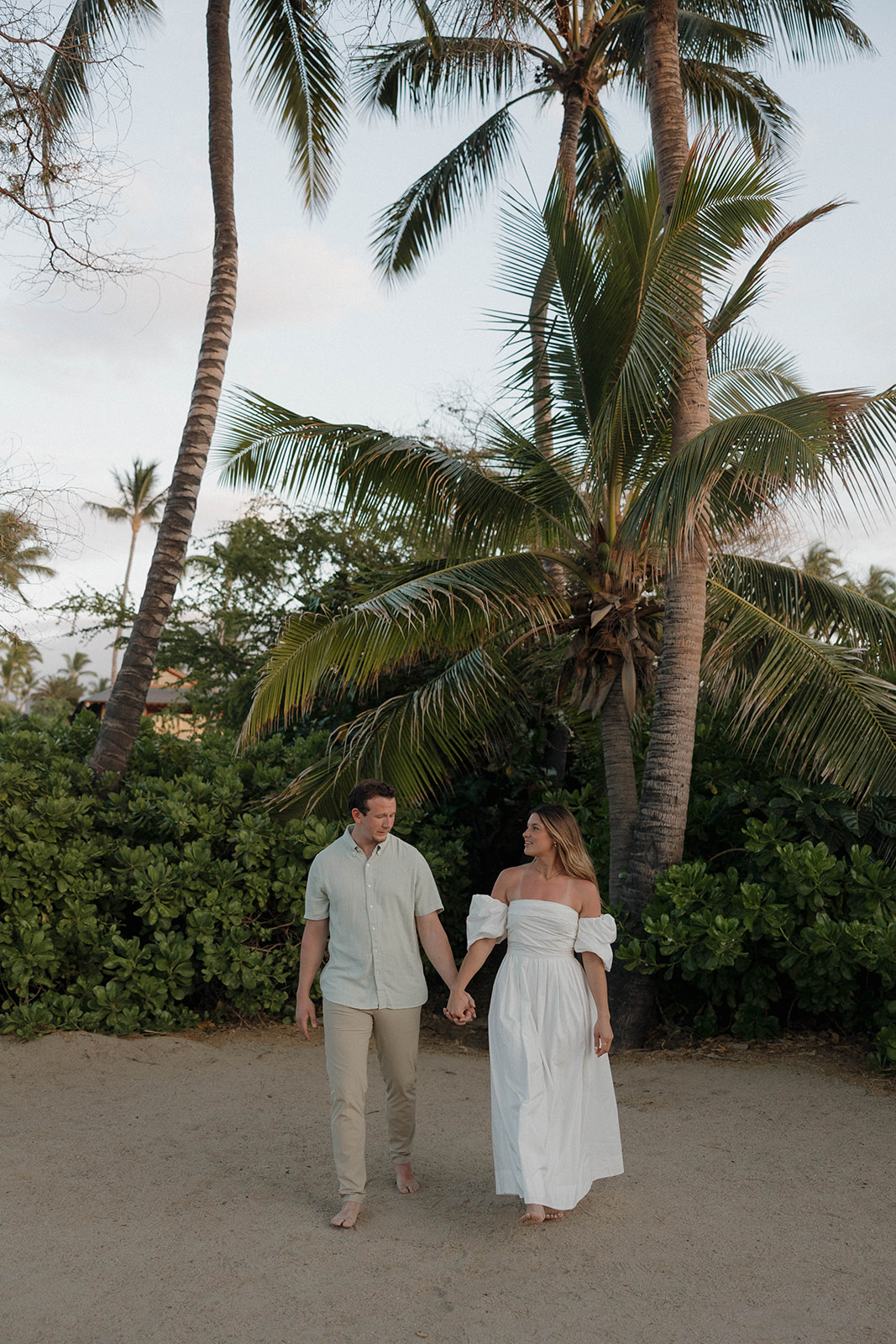 a couple walking hand in hand on the beach featuring what to wear for engagement photos