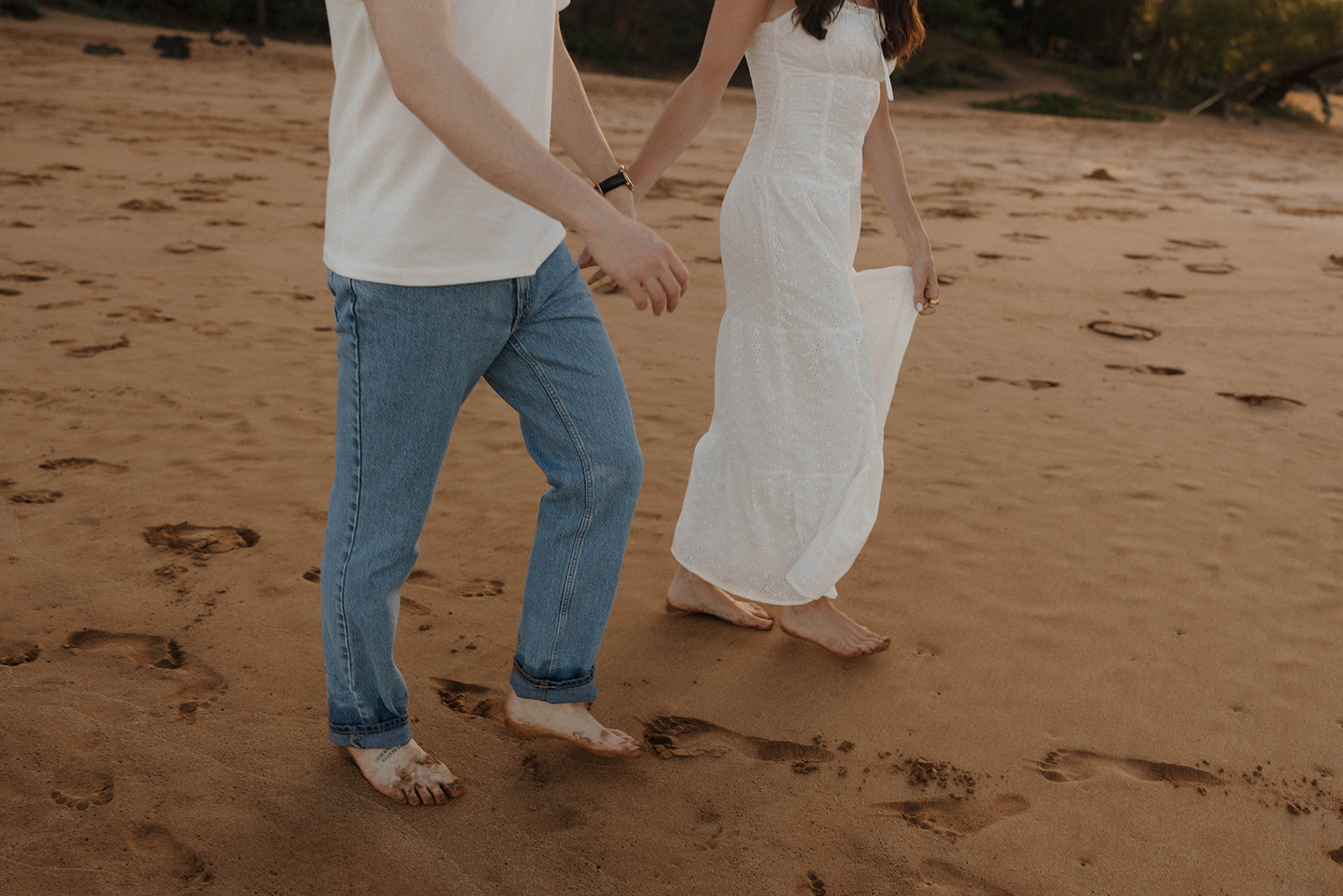 a couple wearing white outfits as they walk on the beach featuring what to wear for engagement photos