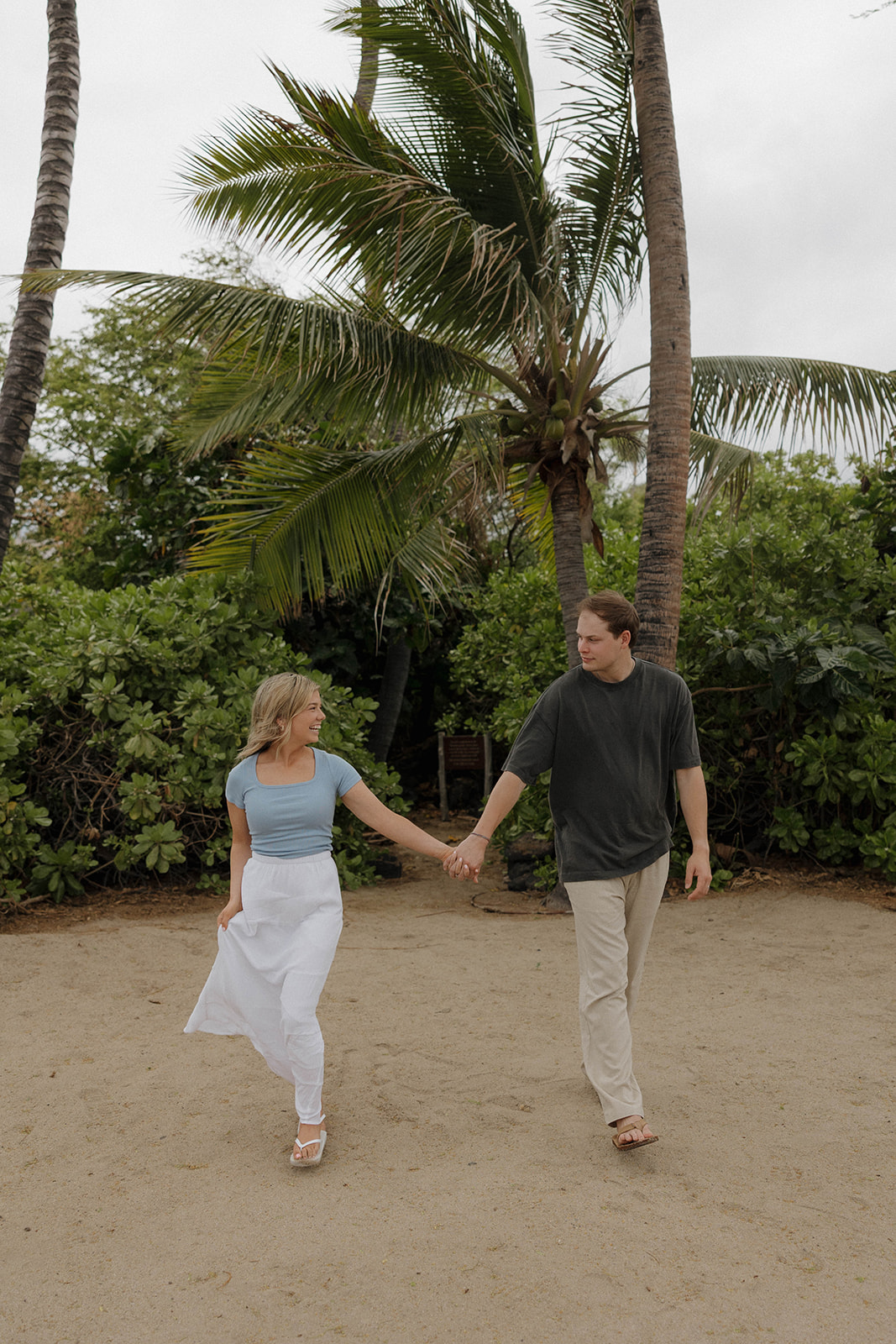 a couple walking hand in hand on the beach in Hawaii for engagement photos 