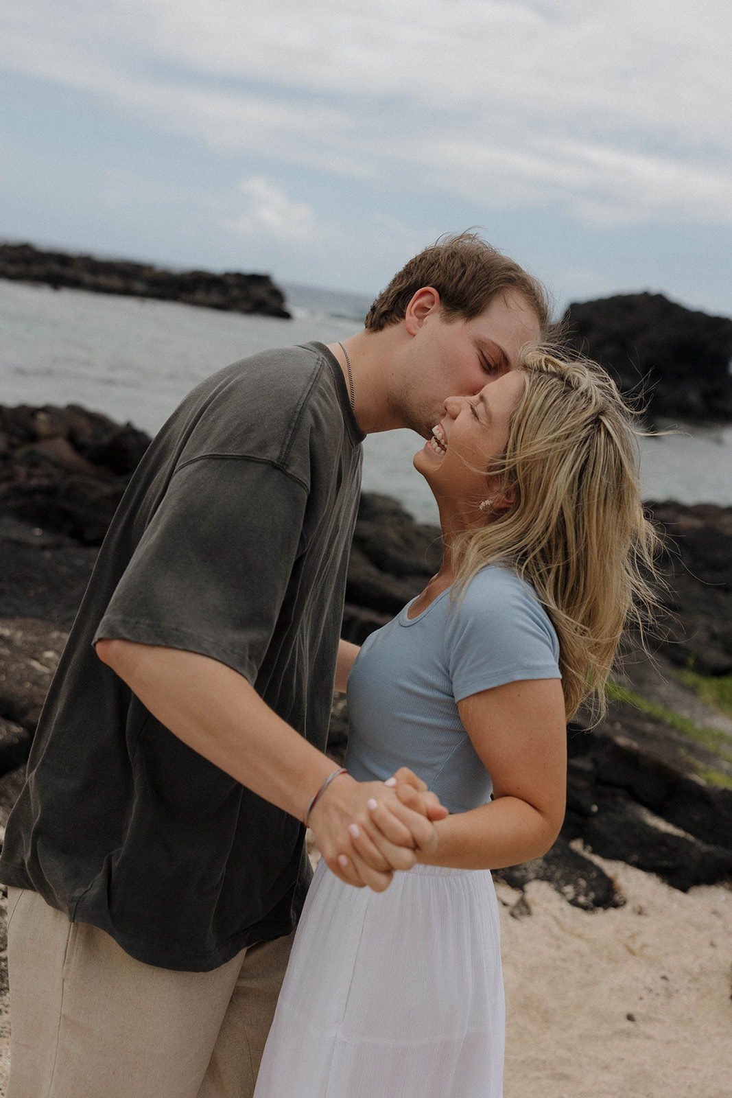 a couple wearing colored shirts as a pop against Hawaii's beaches for their engagement photos