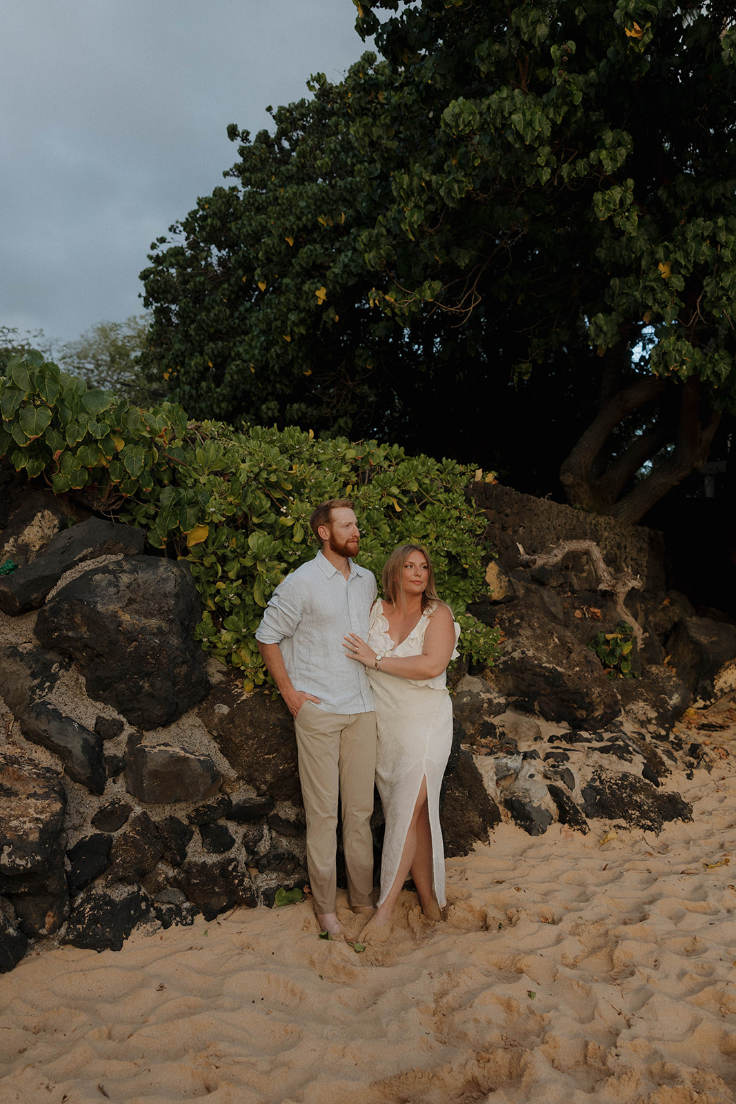 a couple watching the sunset on the beach in Hawaii during their engagement photos