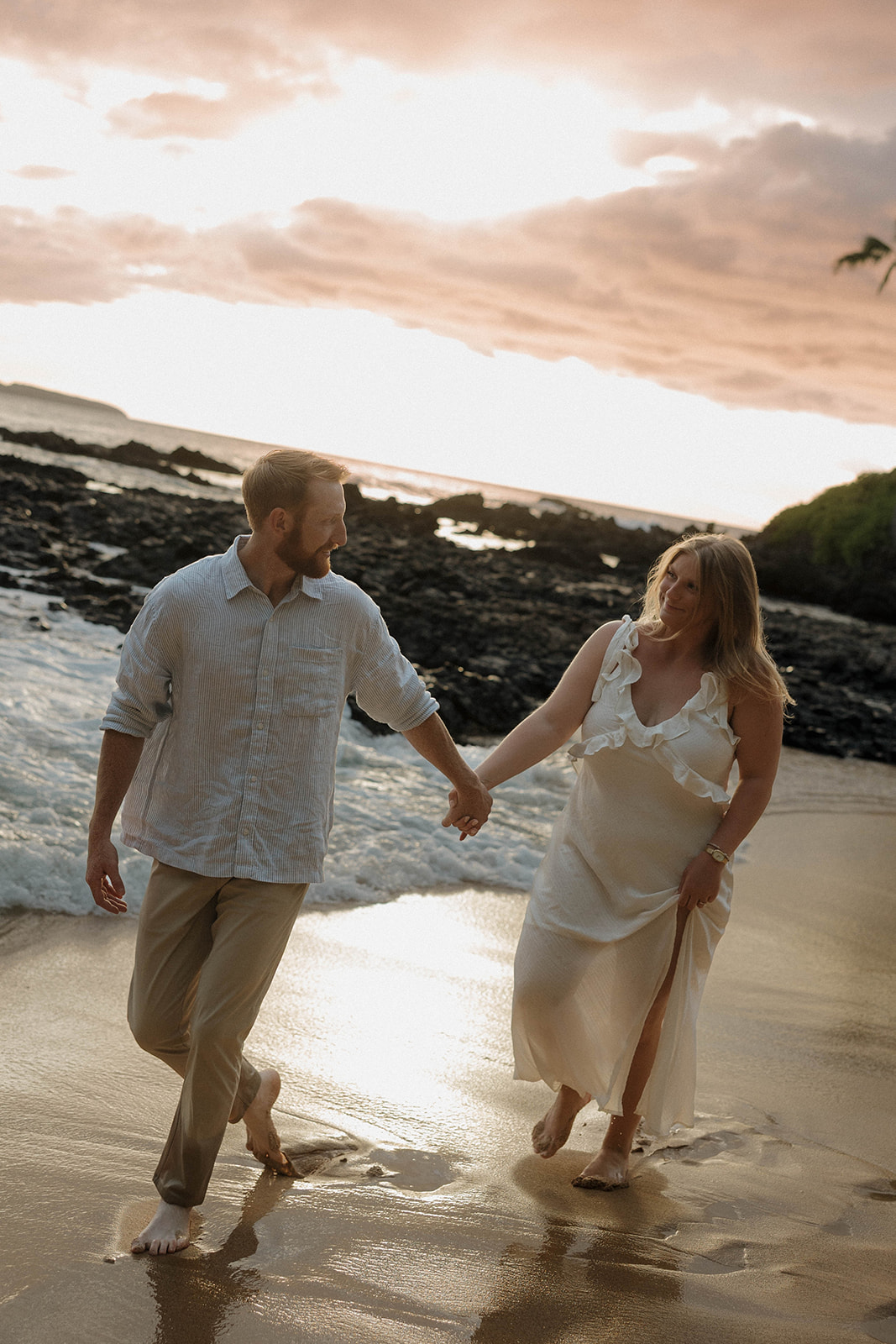a couple walking on a beach during sunset in Hawaii for engagement photos