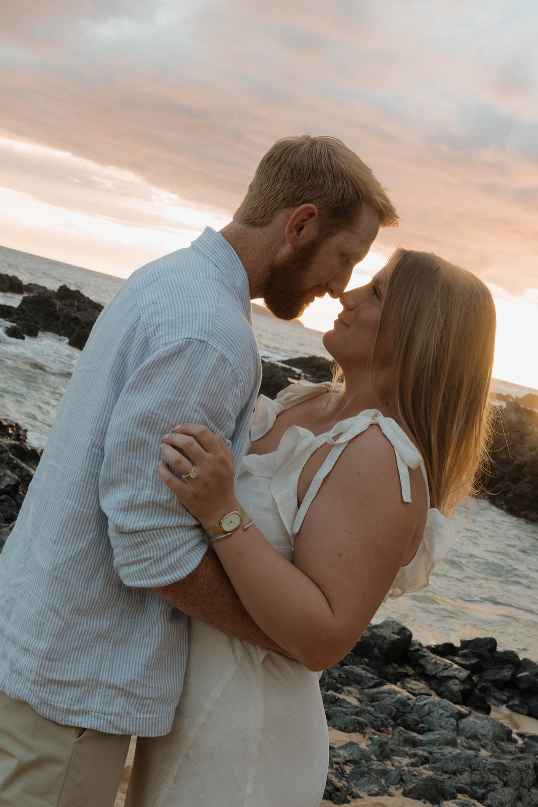 a couple touching noses and looking into each others eyes during beach engagement photos 