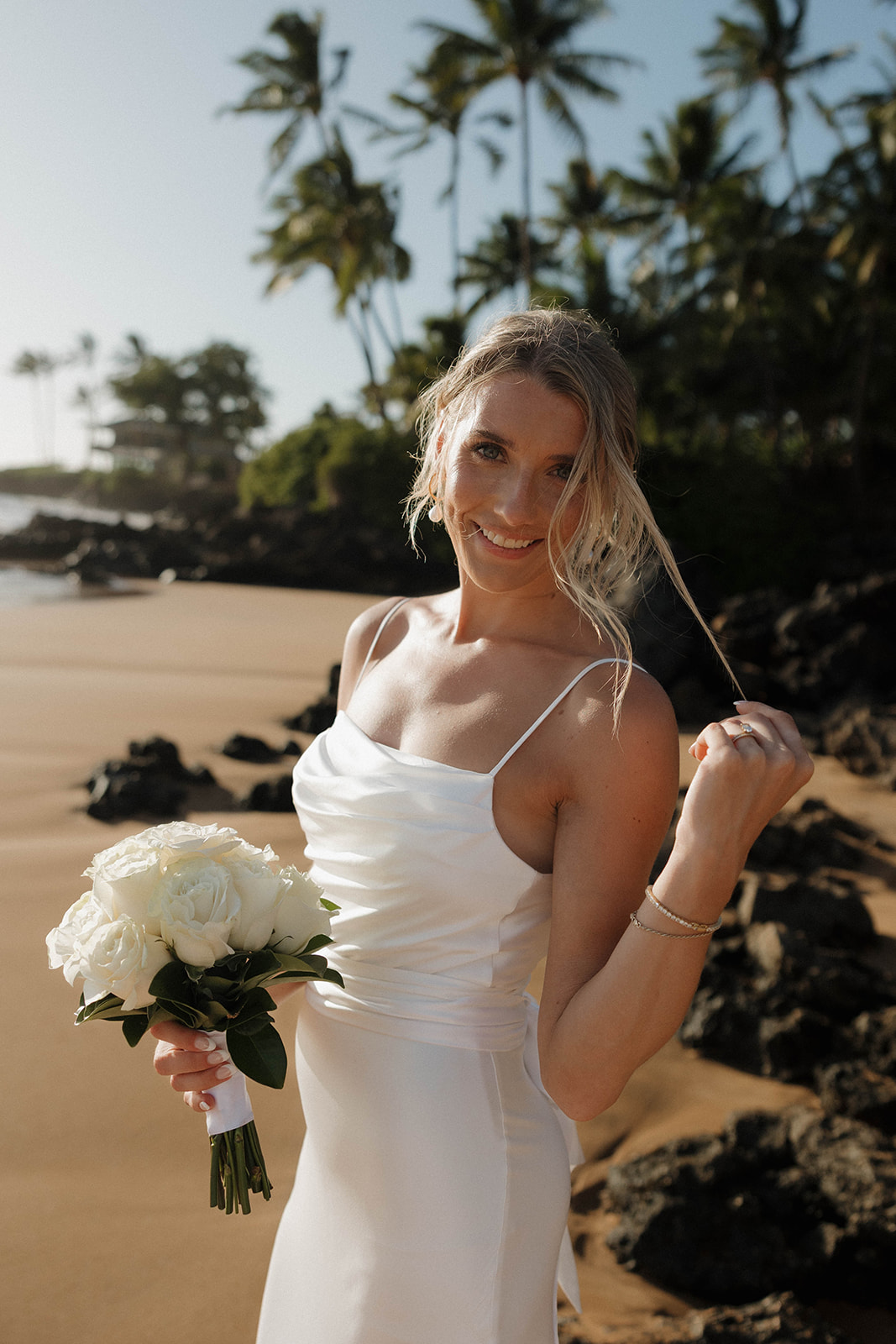 a bride taking portraits on the beach after getting hair and makeup done by a Maui wedding vendor