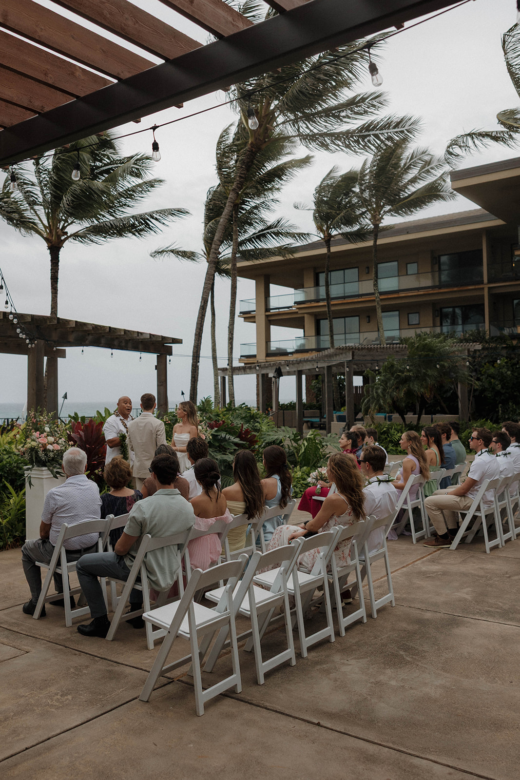 Intimate oceanfront ceremony with guests gathered beneath swaying palms at a destination wedding in hawaii.