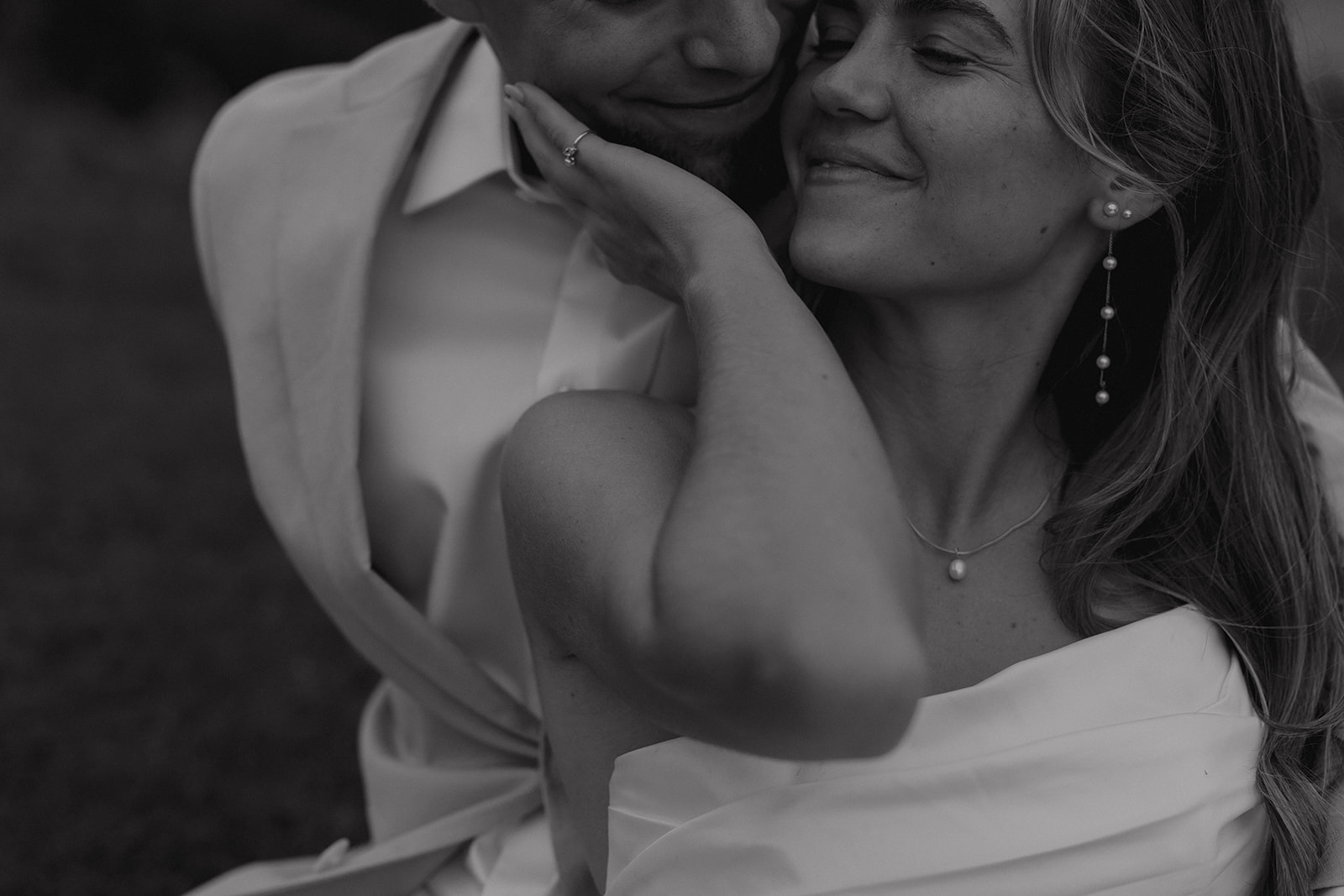 Black and white close-up portrait of the bride and groom embracing with soft, intimate emotion.