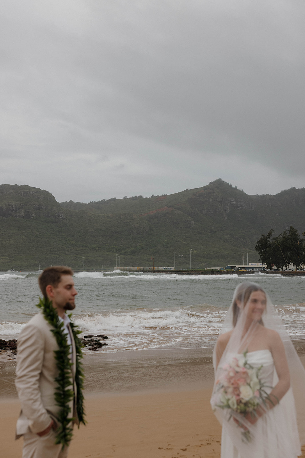 An intimate detail photo the bride and groom standing on the beach for wedding portraits during their destination wedding in Hawaii