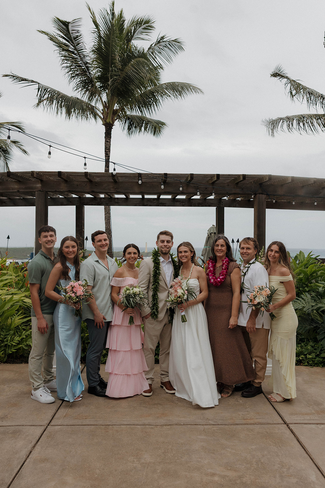 Ceremony portraits of the bride and groom surrounded by their family and island florals at a destination wedding in hawaii.