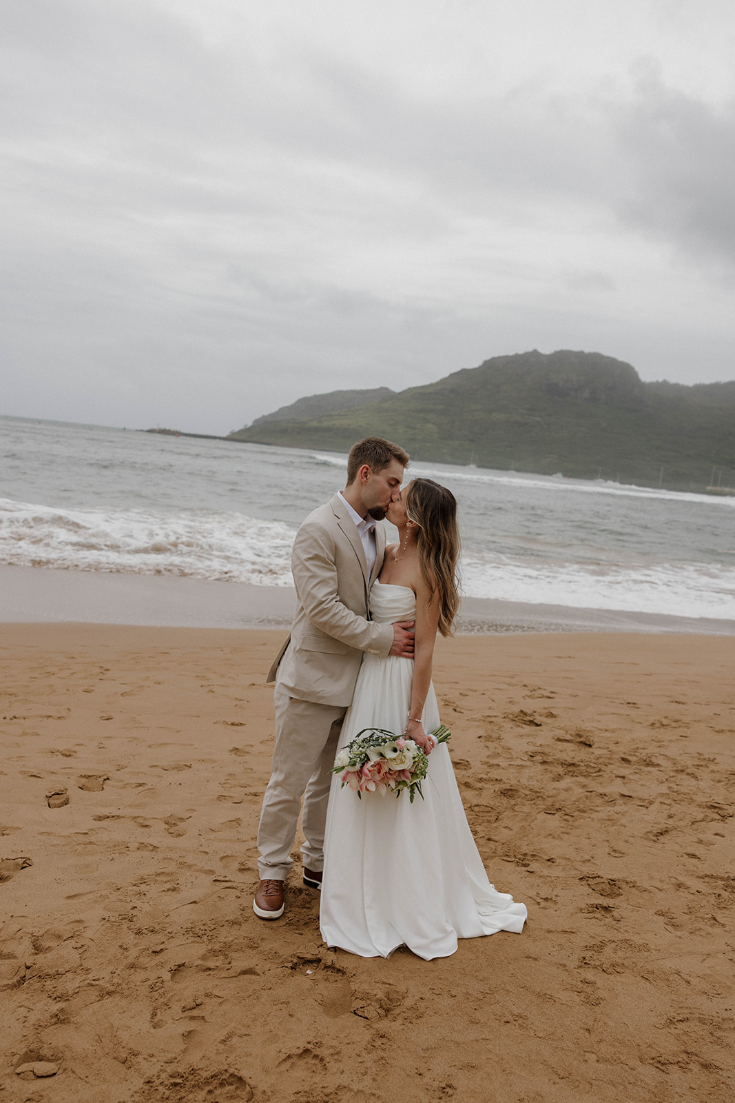 Romantic seaside portraits of the newlyweds kissing on the shoreline during a destination wedding in hawaii.