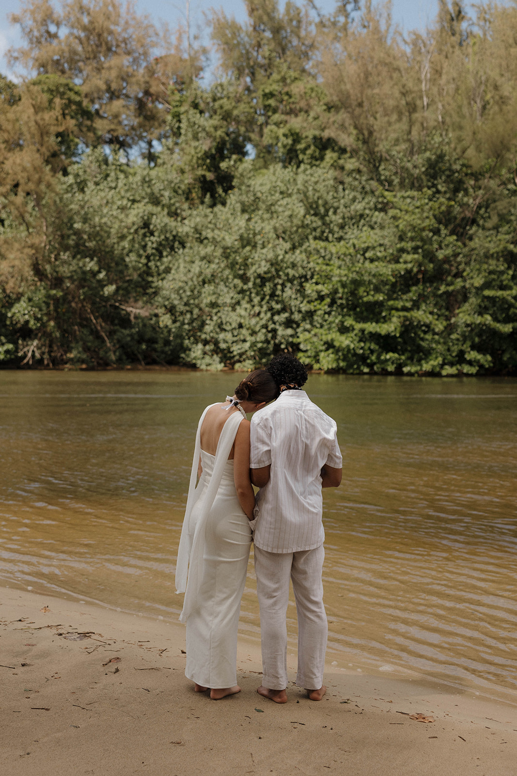 Newlyweds taking a moment after their wedding ceremony looking out over the river after their micro wedding in Kauai.
