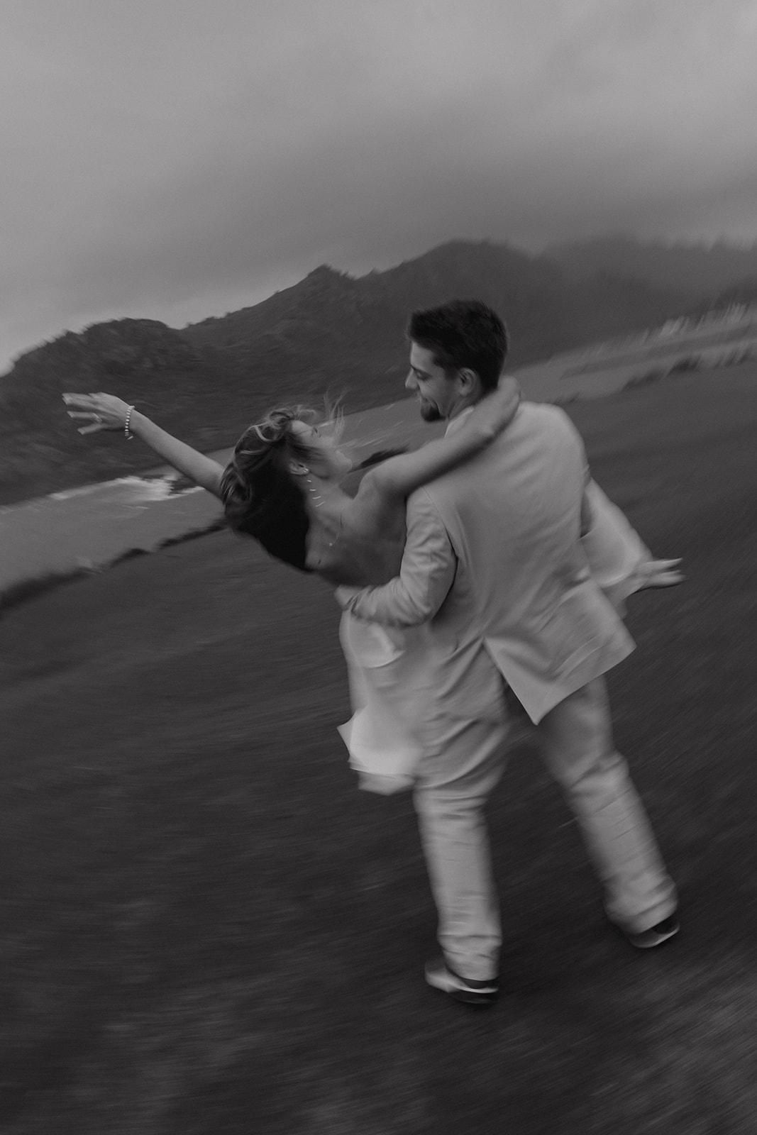 A romantic photo of the groom carrying his wife and twirling her around on the grass at their micro wedding in Kauai.