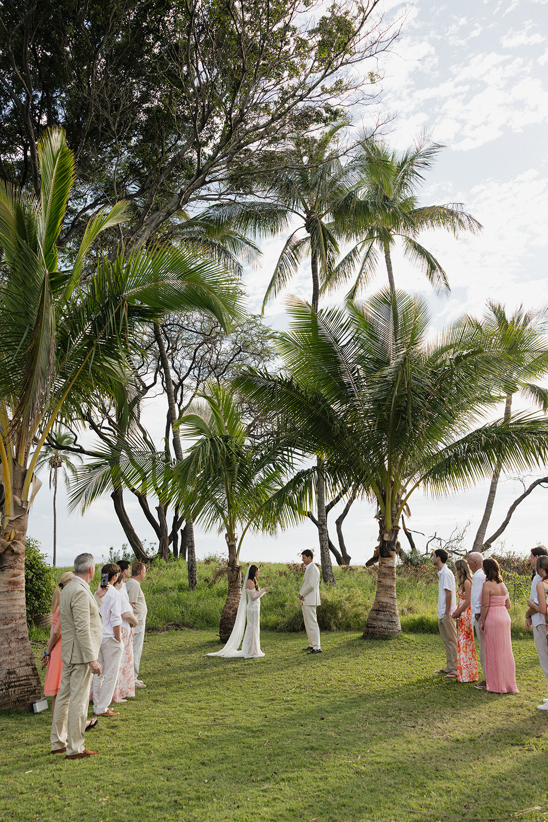Wide shot of intimate Maui elopement ceremony surrounded by palm trees and ocean views
