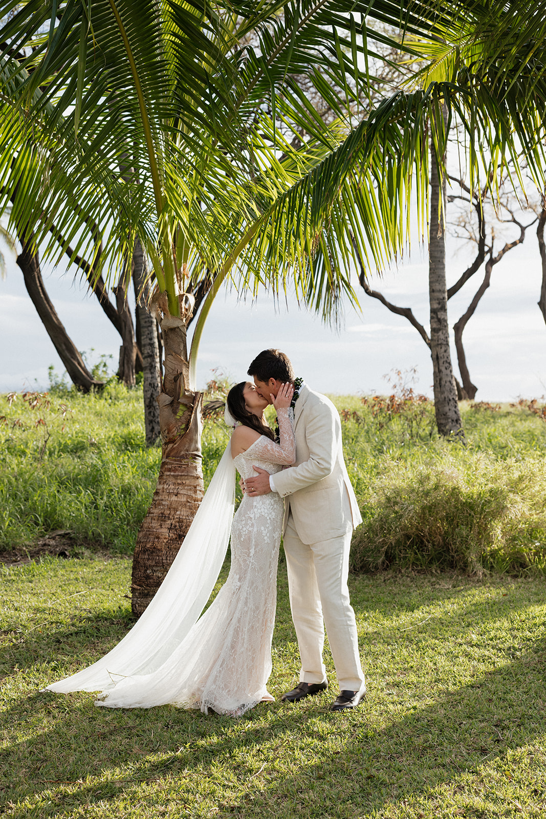 Bride and groom sharing their first kiss under a palm tree during their Maui elopement portraits

