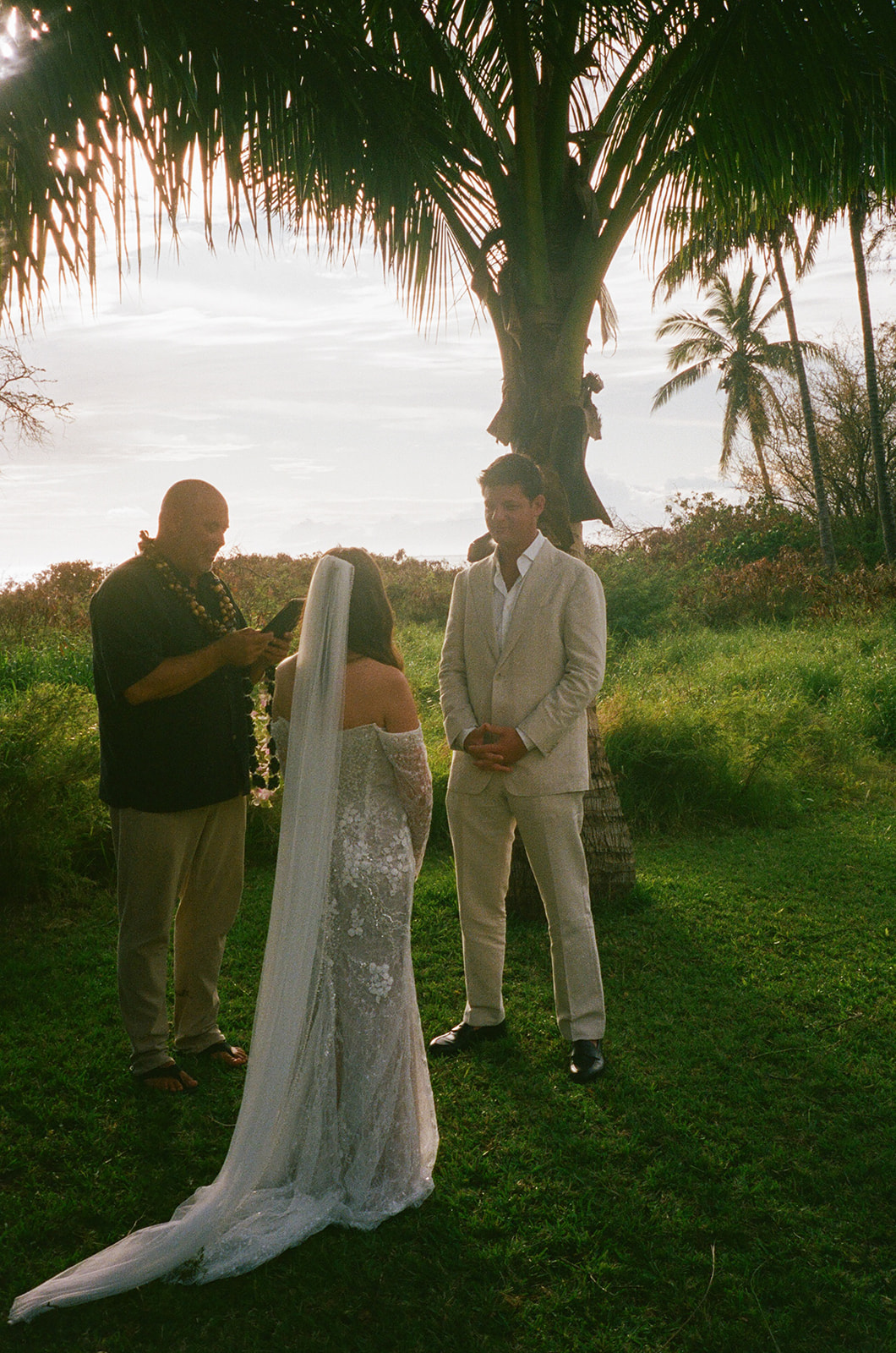 Officiant reading from a book during an intimate outdoor Hawaii wedding ceremony at golden hour
