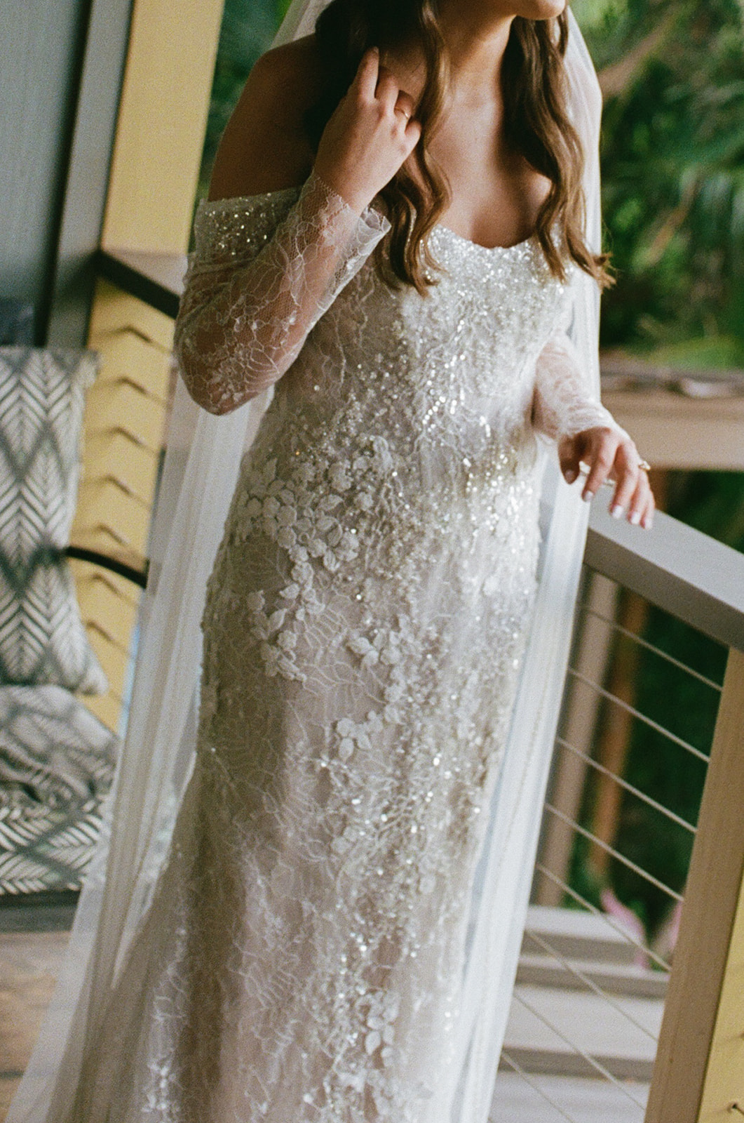Close-up detail of bride's beaded lace wedding gown and veil on a Hawaii venue balcony
