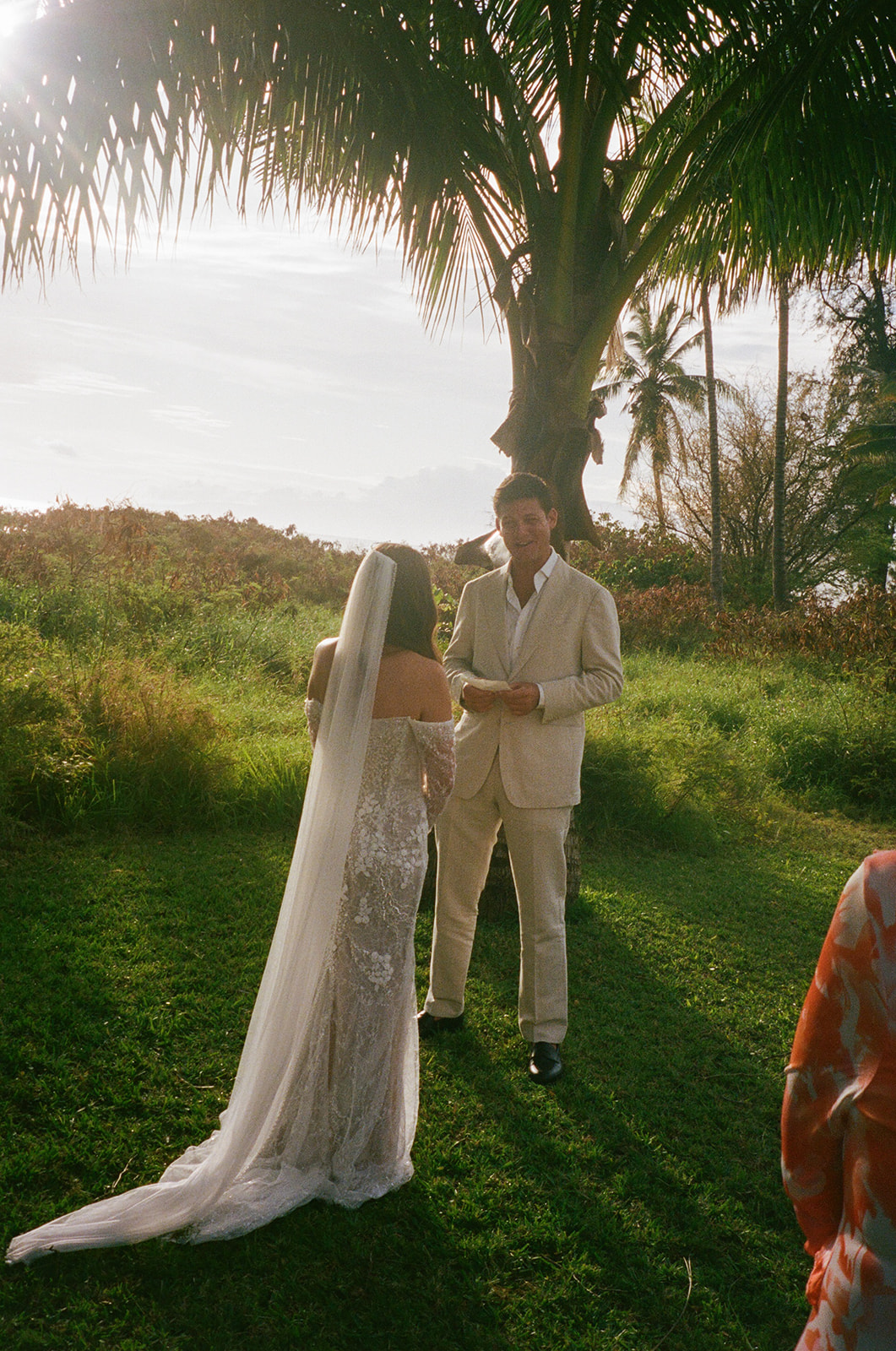 Groom smiling while reading vows to bride during outdoor Hawaii wedding ceremony
